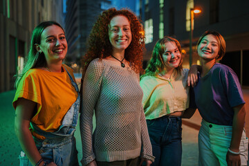 Portrait of a group of young adult women standing together at night time. Four teenage girls...