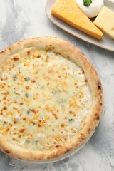 Delicious cheese pizza and different kinds of cheese on light grey textured table, flat lay