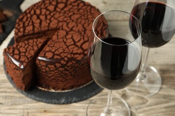 Delicious chocolate truffle cake and red wine on wooden table, closeup