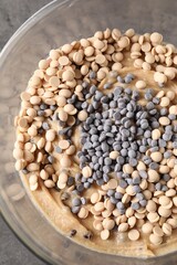 Raw dough with chocolate chips in bowl on grey table, top view
