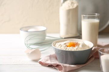 Making dough. Flour with yolk in bowl on white wooden table, closeup