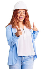 Young latin woman wearing architect hardhat pointing fingers to camera with happy and funny face. good energy and vibes.