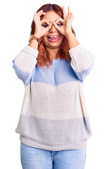 Young latin woman wearing casual clothes doing ok gesture like binoculars sticking tongue out, eyes looking through fingers. crazy expression.