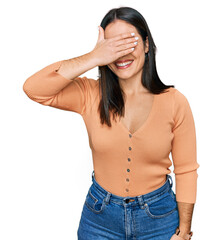 Young hispanic woman wearing casual clothes smiling and laughing with hand on face covering eyes for surprise. blind concept.