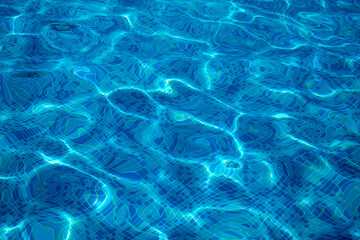 A close-up of the water in a swimming pool, with the sun shining through and creating a beautiful...