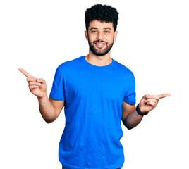 Young arab man with beard wearing casual blue t shirt smiling confident pointing with fingers to different directions. copy space for advertisement