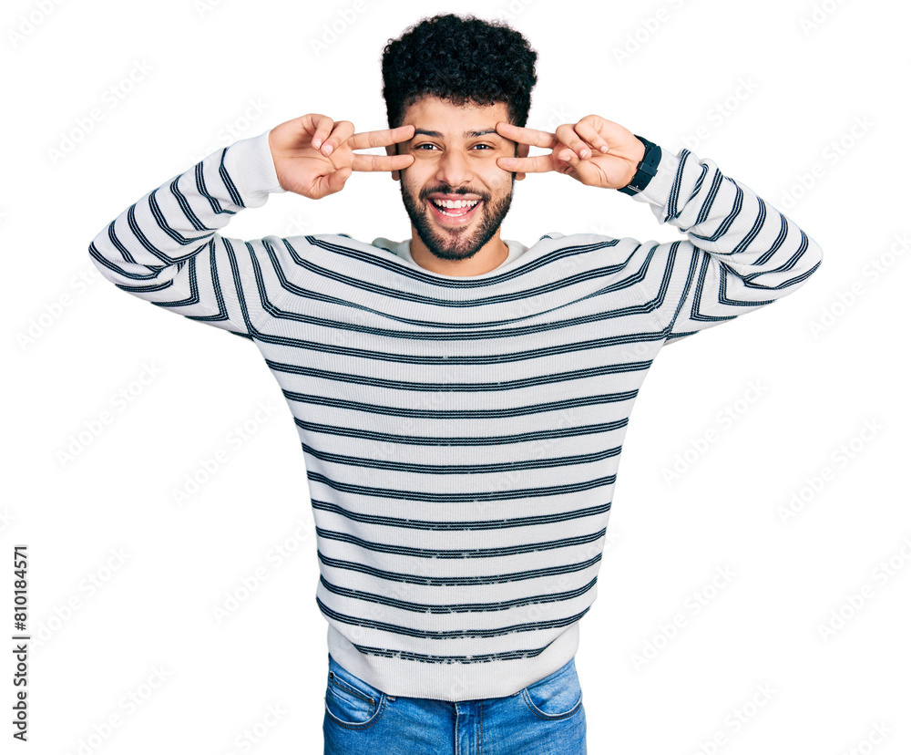 Sticker young arab man with beard wearing casual striped sweater doing peace symbol with fingers over face, 