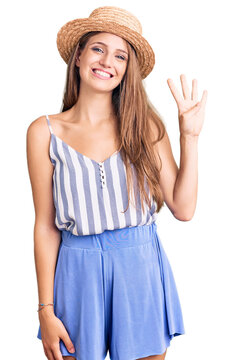 Young beautiful blonde woman wearing summer hat showing and pointing up with fingers number four while smiling confident and happy.