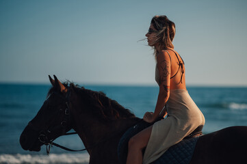 Young woman riding a horse on a beach with a sea in the background