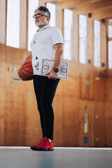 Portrait of an elderly male basketball coach during a practice in a sports hall