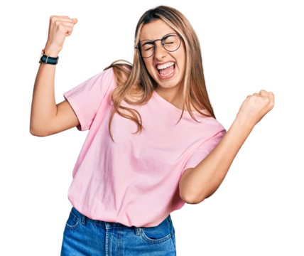 Hispanic young woman wearing casual t shirt and glasses very happy and excited doing winner gesture with arms raised, smiling and screaming for success. celebration concept.