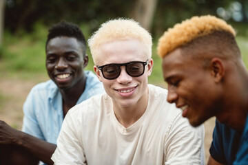 A young albino black man with a group of young people sitting in a row close together, talking or listening attentively. - Powered by Adobe