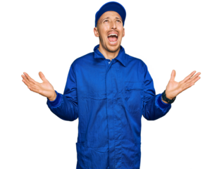 Bald man with beard wearing builder jumpsuit uniform crazy and mad shouting and yelling with aggressive expression and arms raised. frustration concept.