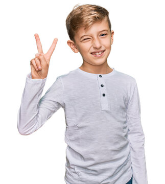 Little caucasian boy kid wearing casual clothes smiling with happy face winking at the camera doing victory sign. number two.