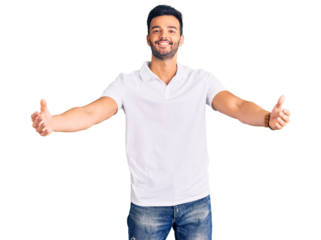 Young handsome hispanic man wearing casual clothes looking at the camera smiling with open arms for hug. cheerful expression embracing happiness.