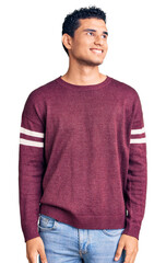 Hispanic handsome young man wearing casual clothes looking away to side with smile on face, natural expression. laughing confident.