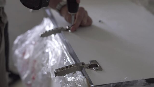 The professional worker attaches the door hinges to the facade. Blurred background.