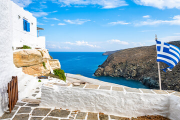 Terrace of Kastro village with white houses and Greek flag and view of sea coast, Sifnos island,...