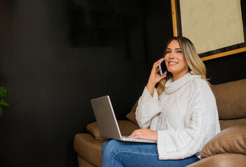 mujer ejecutiva sentada trabajando en el computador mientras recibe una llamada telefónica