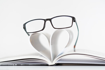 A pair of glasses is placed on top of a heart-shaped paper