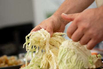 Person manually tearing white cabbage for a homemade recipe. Person manually tearing white cabbage...