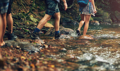 People, legs and hiking with river in forest for journey or outdoor adventure in wilderness. Feet...