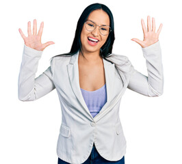 Beautiful hispanic woman with nose piercing wearing business jacket and glasses showing and pointing up with fingers number ten while smiling confident and happy.