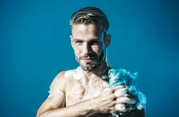 Skin care and body care concept. Smiling man washing body with moisturizing gel. Handsome unshaven...