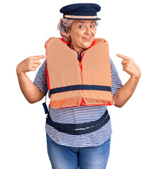 Senior woman with gray hair wearing nautical lifejacket pointing finger to one self smiling happy and proud