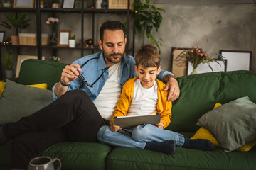 Obraz premium Father look son while he play video games or browse internet on tablet