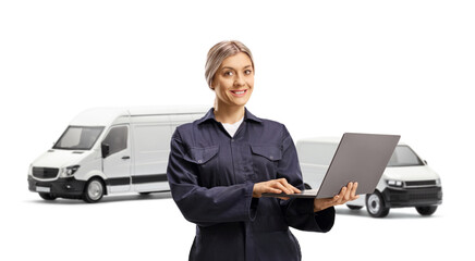 Female mechanic worker wearing overall uniform and holding a laptop computer in front of vans
