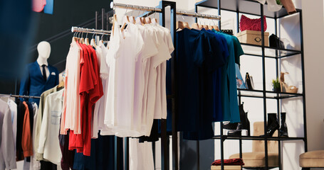 Modern boutique filled with casual wear, multiple racks with fashionable merchandise. Interior of...