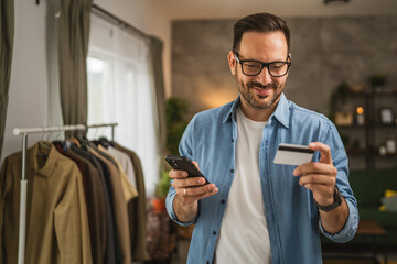 Portrait of adult man shop online with cellphone and hold credit card at home