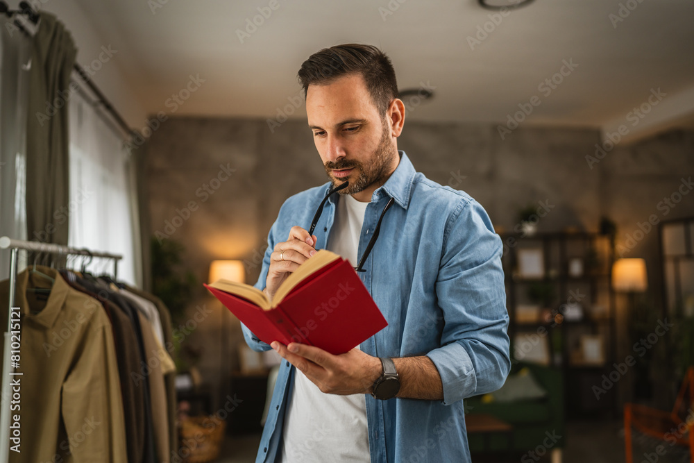 Wall mural Portrait of adult caucasian man with eyeglasses read book at living room happy and relax