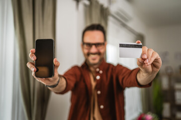 Portrait of close up of adult man hand hold credit card and cellphone