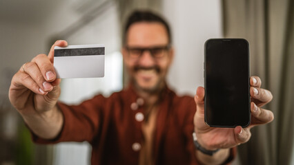 Portrait of close up of adult man hand hold credit card and cellphone
