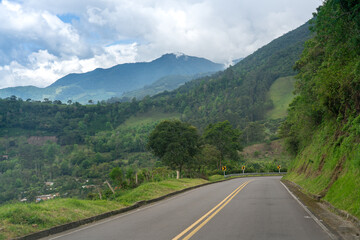 Fototapeta premium Road going down a hill in a Colombian landscape of mountains.