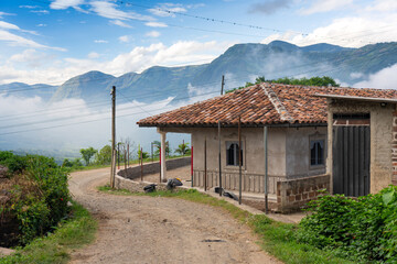Dirt road with a red tile house and mountains in the background in a rural area of Colombia