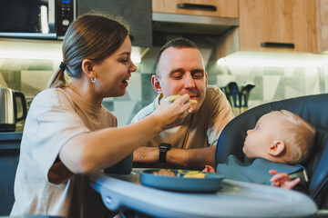 The first complementary food for a baby. A mother feeds puree to her 6-month-old son.