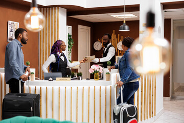African American couple man an woman standing at hotel reception checking in at reception, waiting...