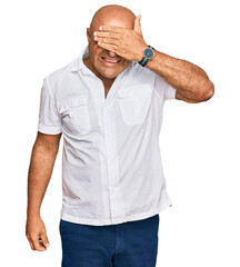 Mature middle east man with mustache wearing casual white shirt smiling and laughing with hand on face covering eyes for surprise. blind concept.