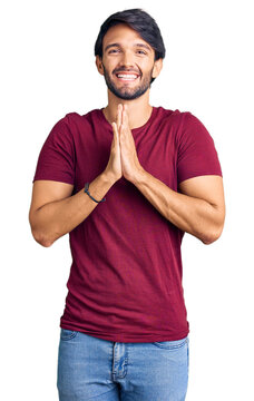 Handsome hispanic man wearing casual clothes praying with hands together asking for forgiveness smiling confident.