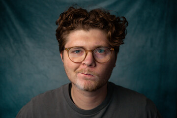 Man with Glasses Confused Staring at Camera Portrait with Blue Background.