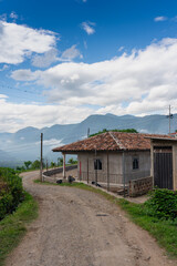 Dirt road with a red tile house and mountains in the background in a rural area of Colombia