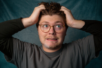 Man with Glasses Stressed Pulling Hair Portrait with Blue Background.
