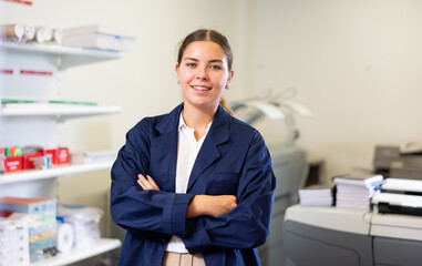 Fototapeta premium Portrait of joyful young female specialist in uniform with crossed arms in the middle of the typography