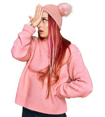 Young caucasian woman wearing casual clothes and wool cap surprised with hand on head for mistake,...