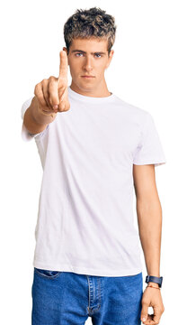 Young handsome man wearing casual white tshirt pointing with finger up and angry expression, showing no gesture
