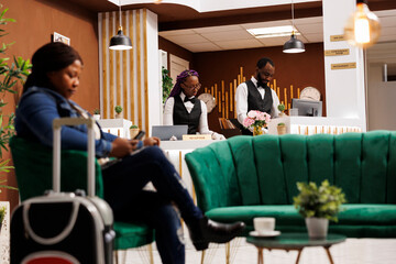 African American front desk staff working together behind reception counter, maintaining guest...