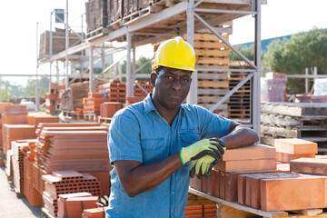 Worker stacking bricks in warehouse of building materials